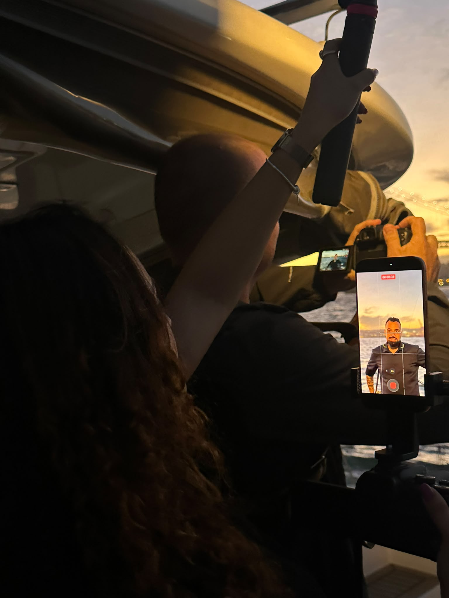 Priscila a bordo, ao pôr do sol, a filmar com o telemóvel durante um evento